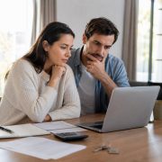 Pareja comparando escenarios hipotecarios en un ordenador antes de comprar una vivienda